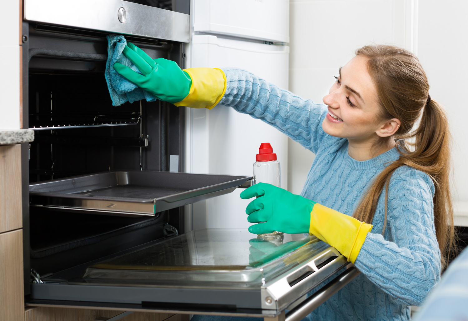 Young maid doing oven clean-up